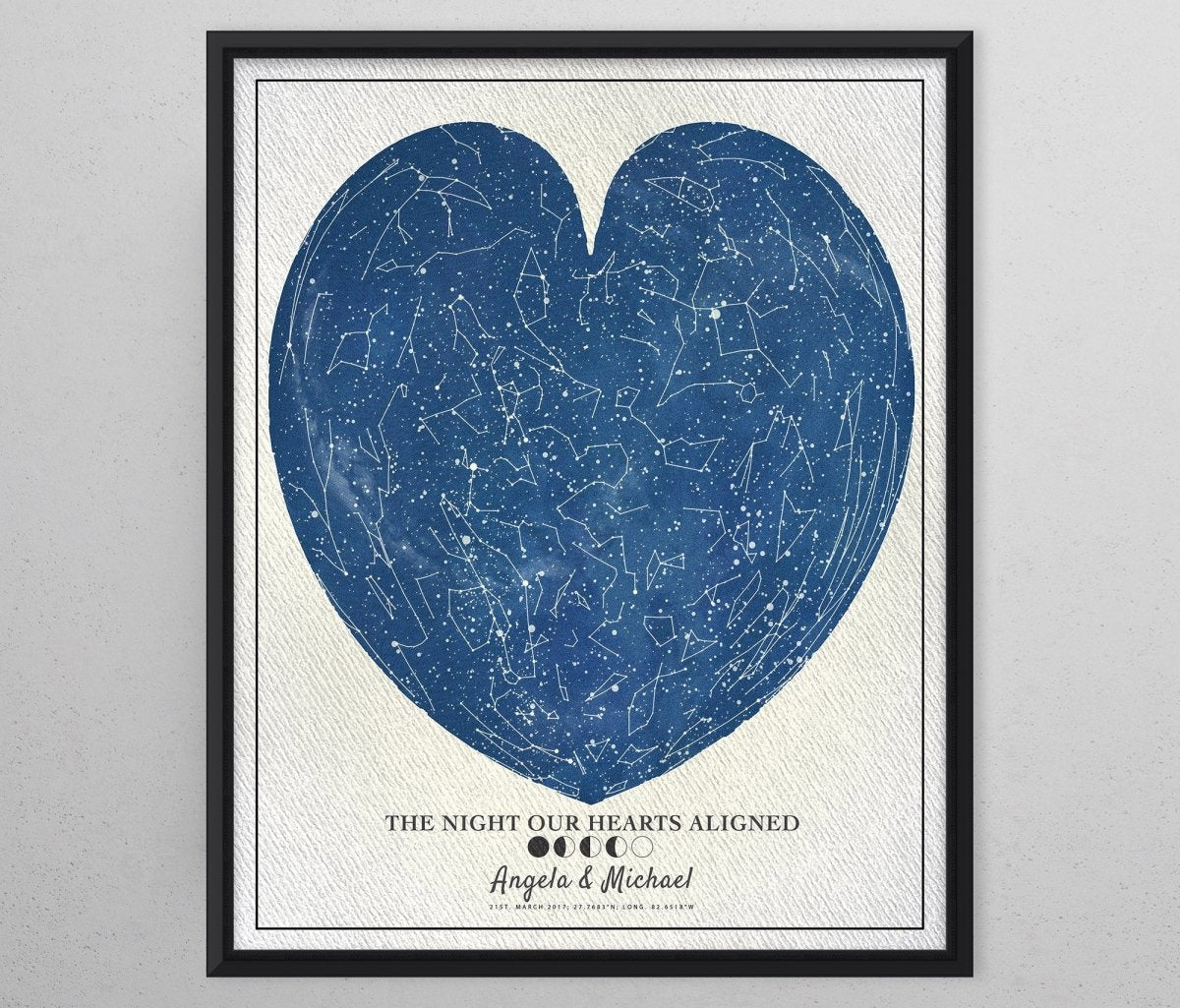 A framed Heart Star Map gift print with a blue heart-shaped constellation design on a white background, with text underneath the heart. Framed in a black frame.